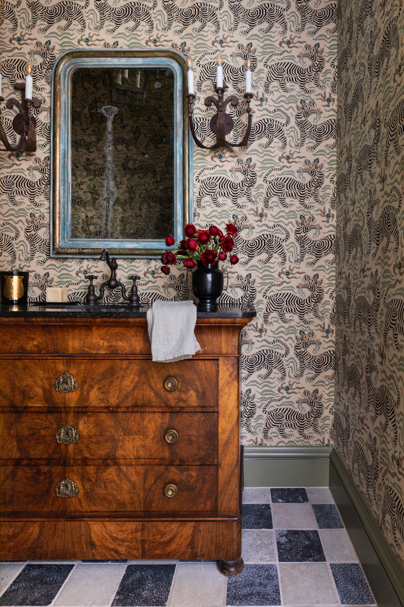 Interior view of a room with a wooden chest of drawers, a mirror and decorative elements