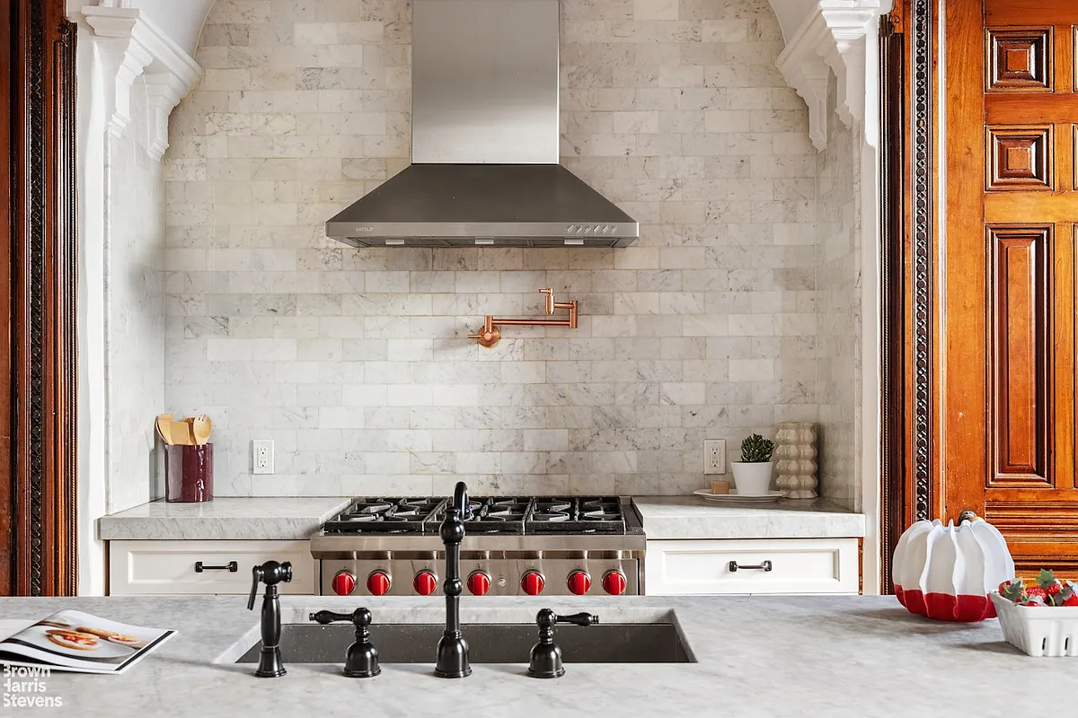 Detail of the kitchen with cupboards and a stove in a niche with a stainless steel extractor hood