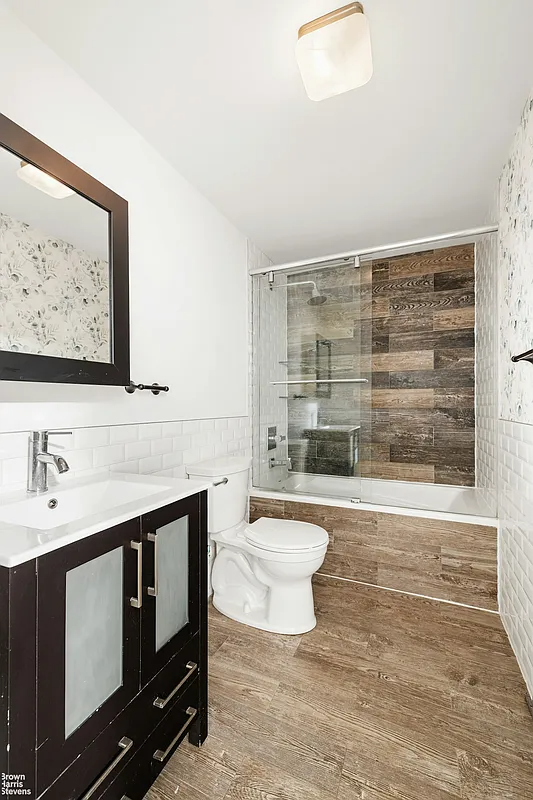 Bathroom with faux wood tiles on the floor and bath surround mixed with white subway tiles