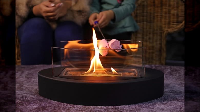 People roast marshmallows on a smokeless, portable tabletop fireplace