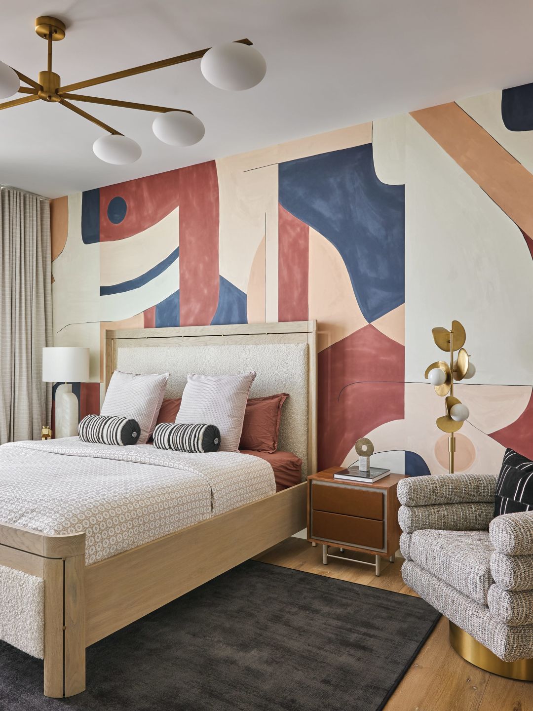 Hand-painted wallpaper doubles as wall art, and rounded furniture softens the space.