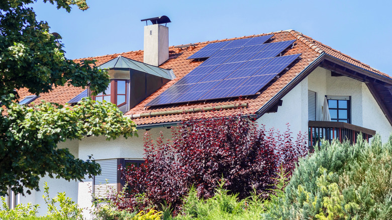 A white house with a red roof has installed solar collectors