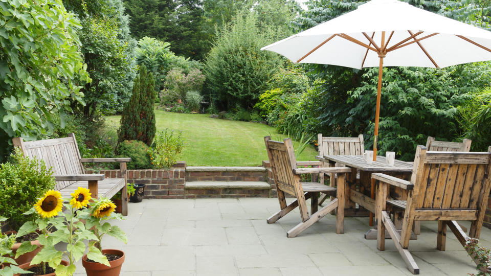 Terrace in the foreground of the garden with a bench and table and chairs to the side