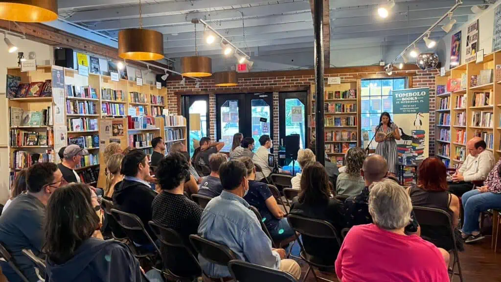 A group of people watches a poet on stage in a bookstore