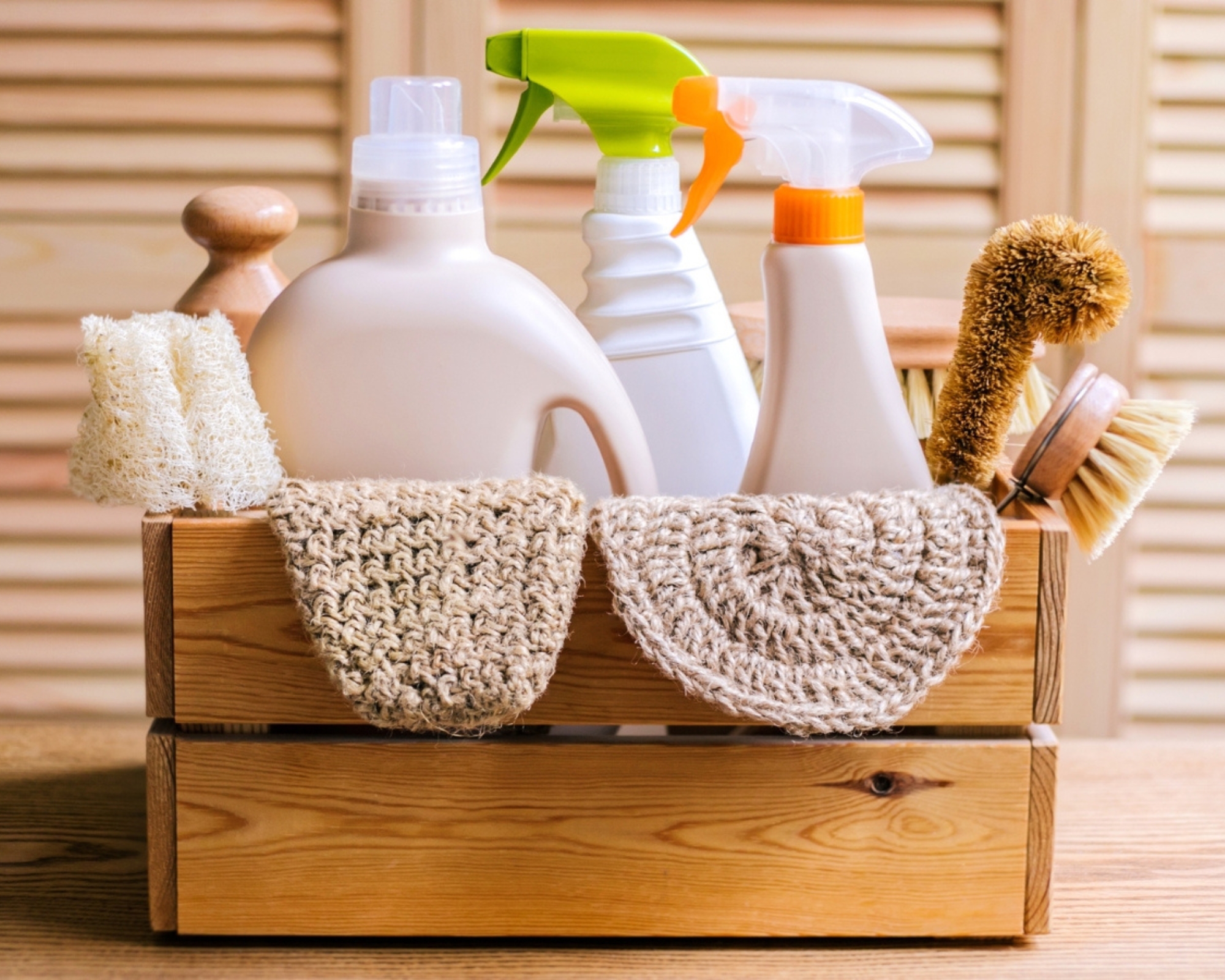 Cleaning set for different surfaces at home, including bottles, sprays, towels and brushes in a wooden box