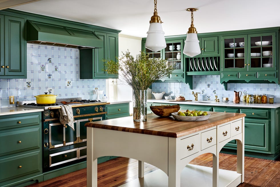 Kitchen with green cupboards, a white island with a wooden top and blue back splash tiles