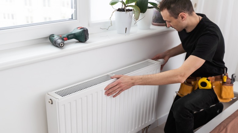 A repair man works on a white cooler