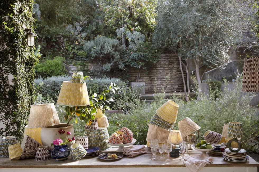 Arrangement of colorful lampshades and tableware in a garden environment.