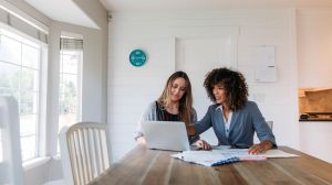 Two women in front of a computer who talks about the deposit and the down payment in one house