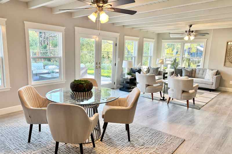 Dining table with padded chairs on one side of the family room with a seat lounge on the other side.