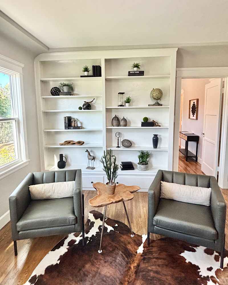 Decorated built -in shelves in Home Office with two arm chairs.
