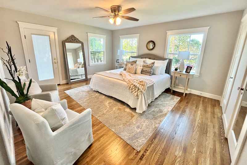 Neatly manufactured bed in a slightly filled renovated bedroom.