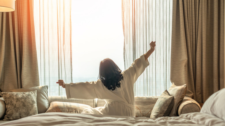 Woman sits on the bed in the morning