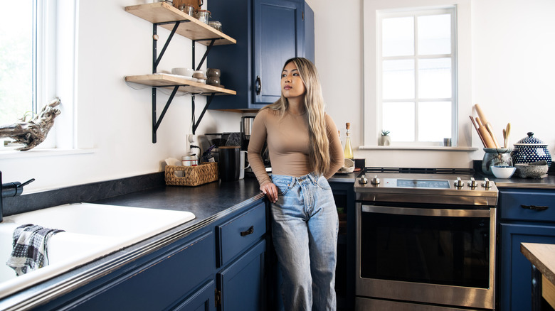 Woman leans against blue cupboards