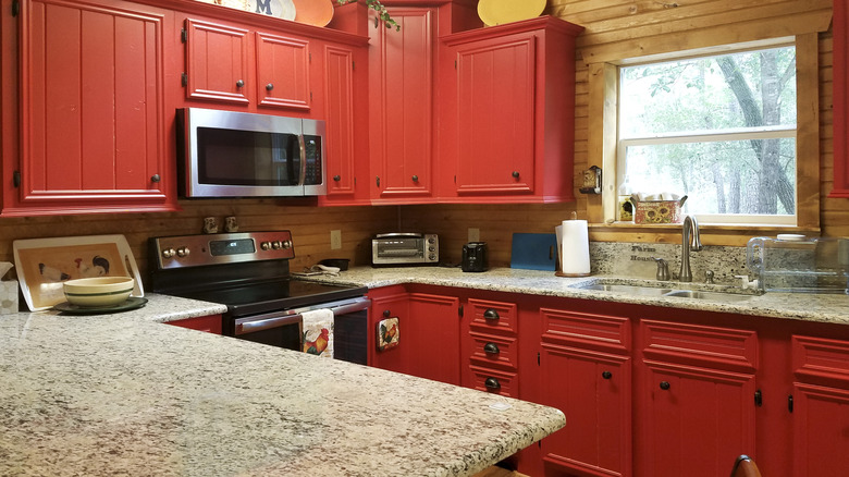 A kitchen with dark red cupboards