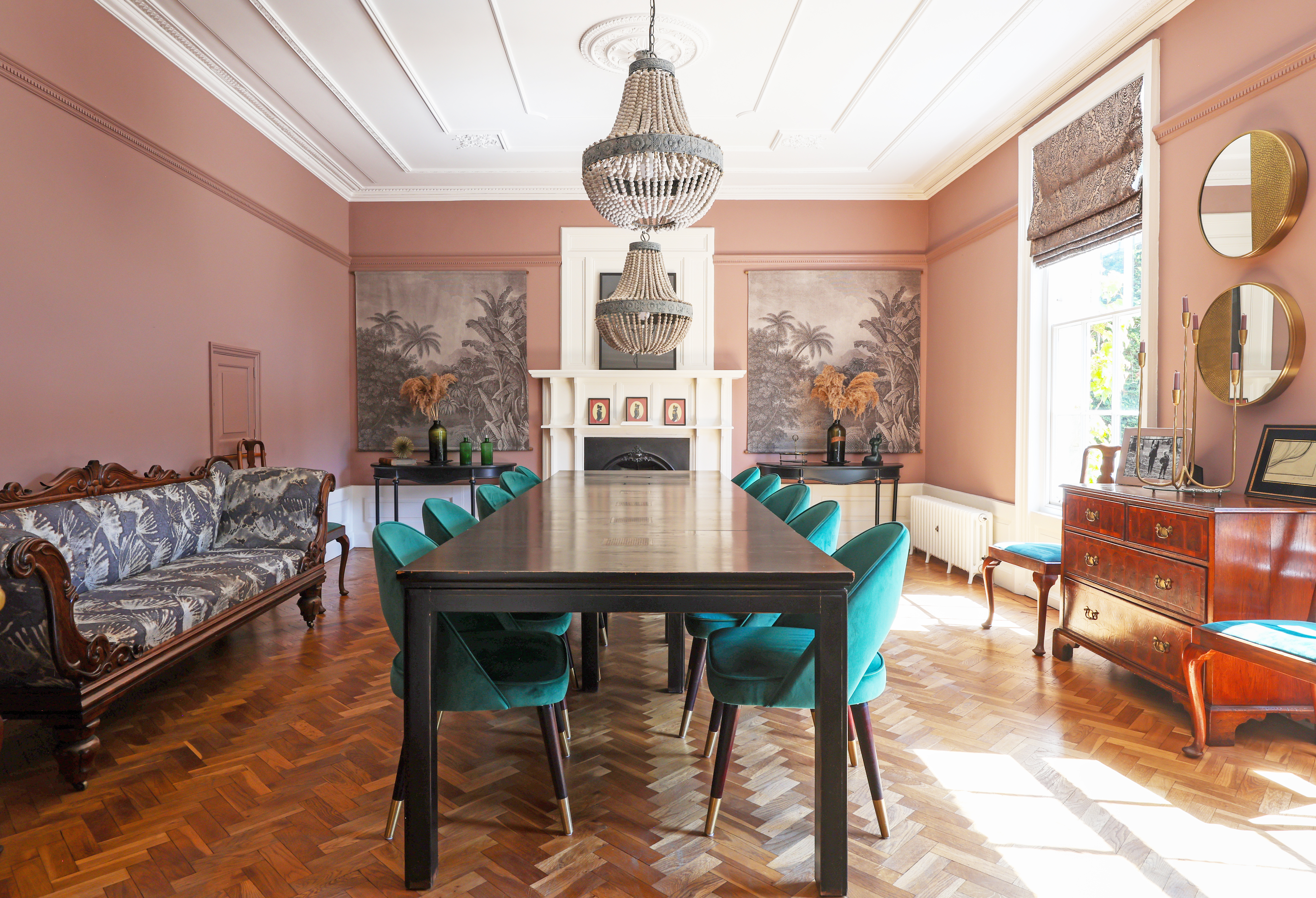 Dining room in the Histon Manor with a long dark wooden table and blue -green velvet chairs.