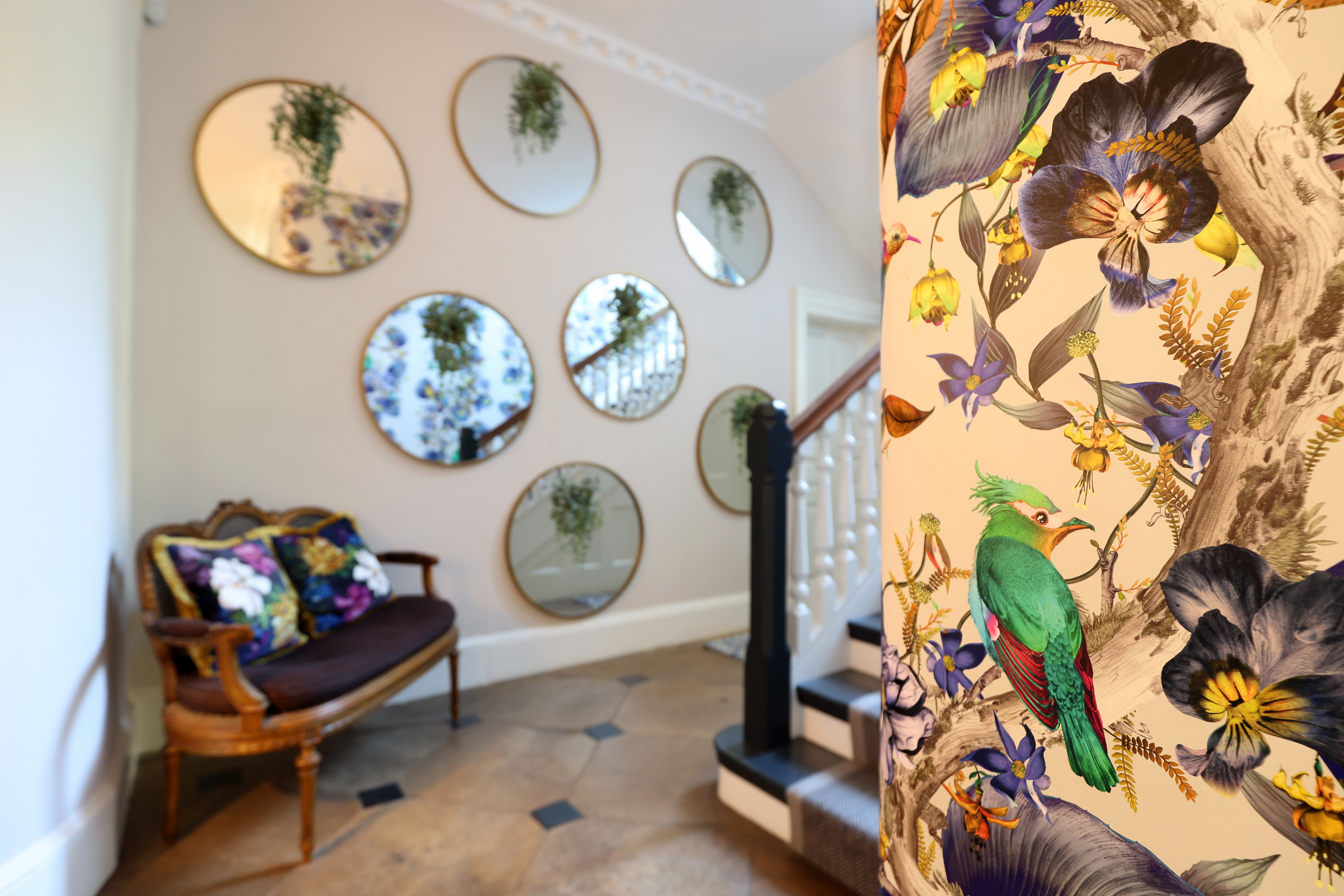 Flower wallpaper and circular mirror in a renovated manor house.