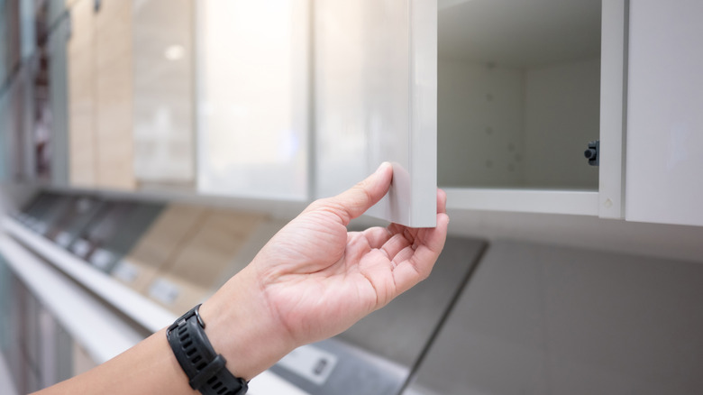A hand opens a kitchen cabinet