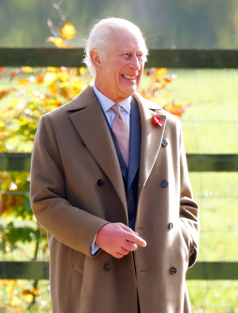King Charles smiles in a brown coat