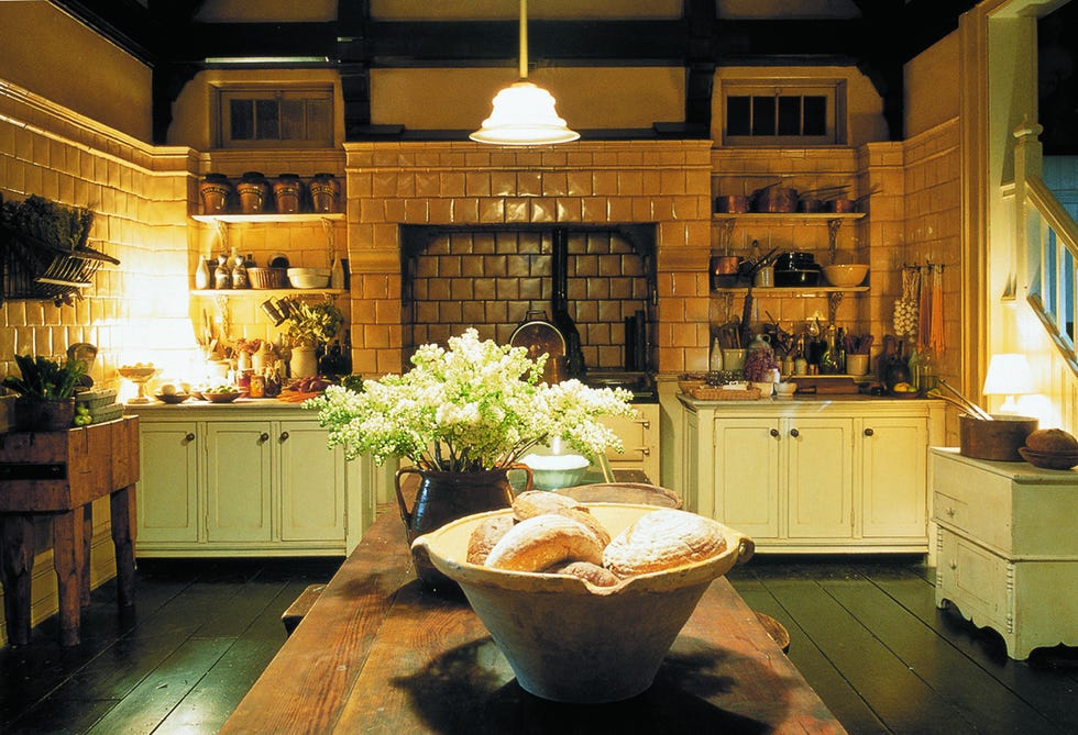 Rustic cuisine presents wooden table with bread and flowers, tiled walls and various kitchens.