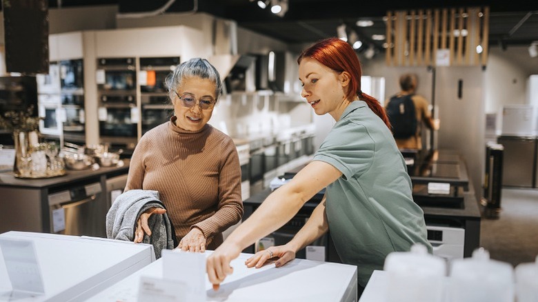 Sales employees help customers choose kitchen appliances.