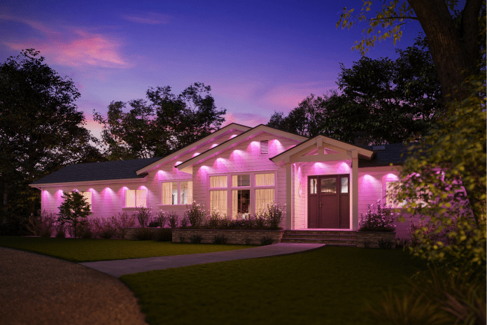 A beautifully illuminated house with a permanent prism outdoors, which shows a lively pink lighting around the exterior, surrounded by trees and a well -groomed lawn that plays against a sky at dusk.