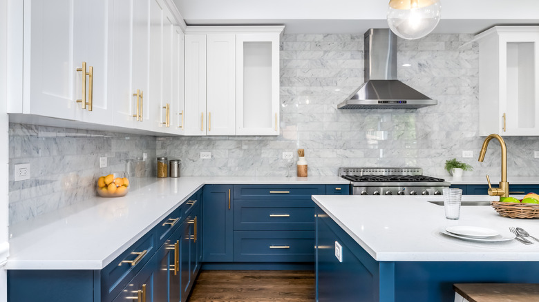Modern kitchen with white worktops and white upper cabinets with blue lower cabinets.