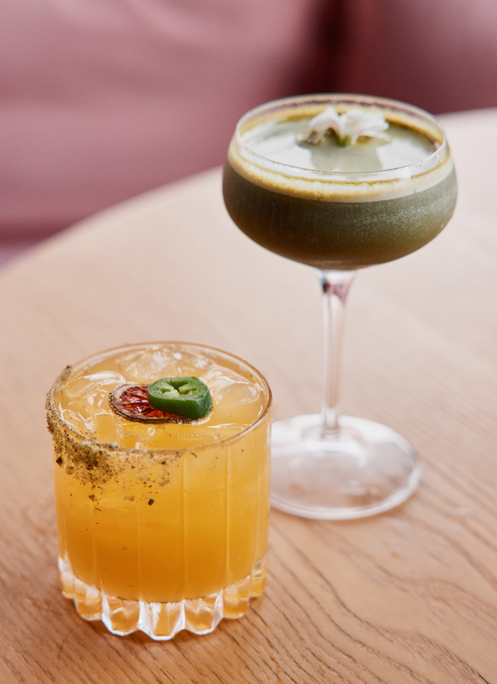 A matcha martini (right) and an orange drink garnished with a slice of jalapeño pepper (left)