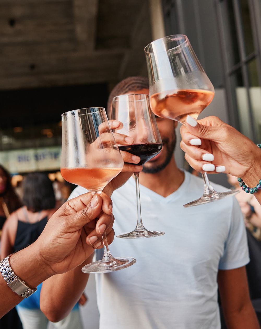 Three hands hold wine glasses and clink together