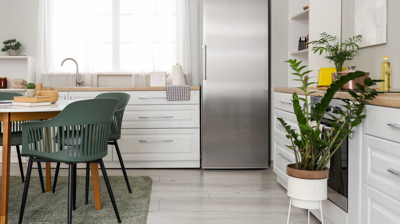 An elegant white kitchen with gray-green chairs and carpet