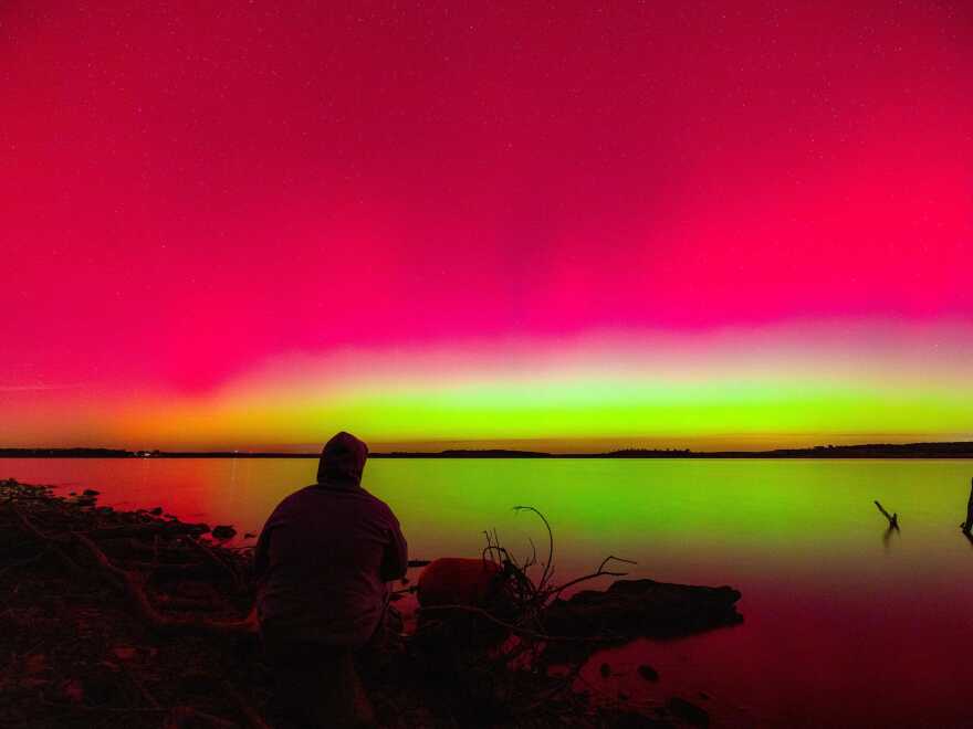 A person watches the Northern Lights over Hulah Lake in northern Oklahoma on Tuesday.