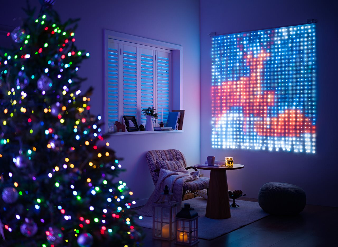 A Christmas tree next to a light display on the wall depicting reindeer.