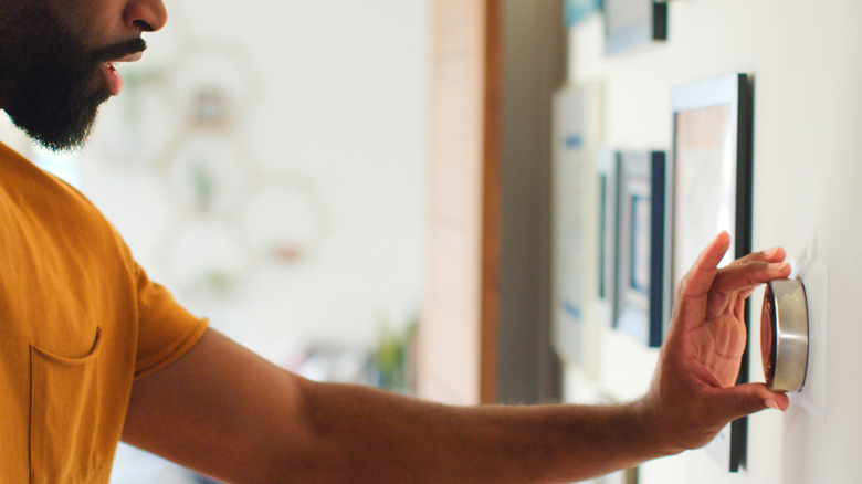A man adjusts the thermostat in his house