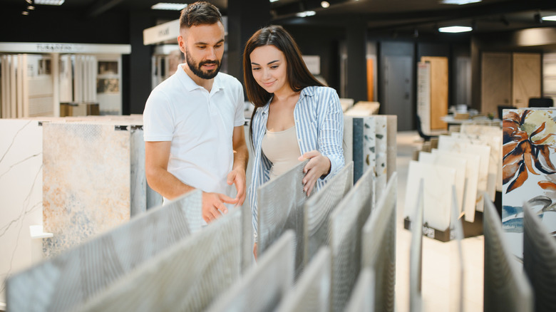 Couple choosing ceramic tiles for kitchen or bathroom in a hardware store.